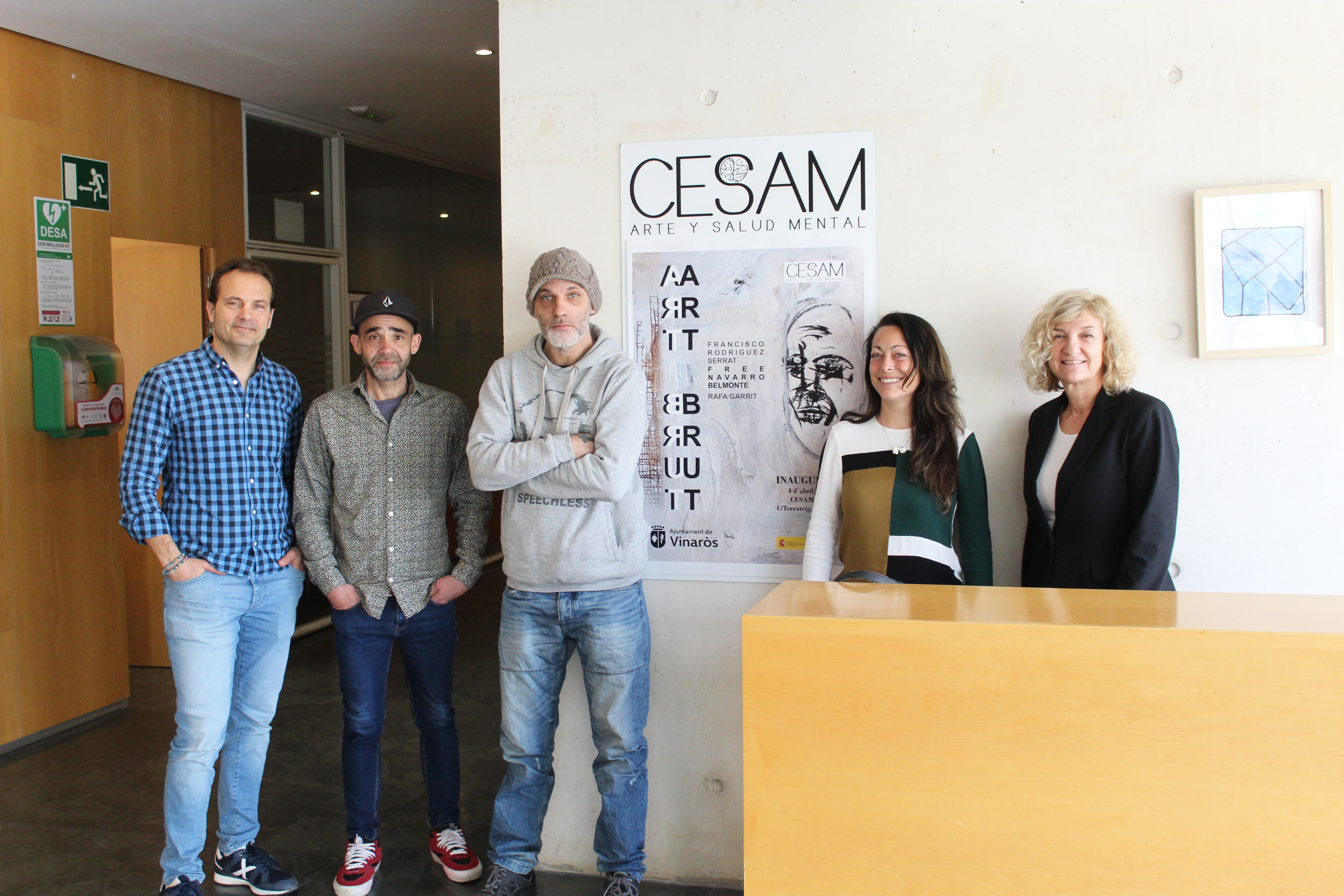 Los artistas posando junto al cartel de la exposición.