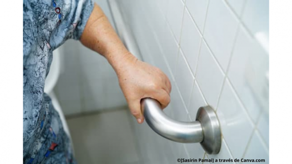 Persona mayor apoyándose en una barra anclada a la pared al lado del inodoro.