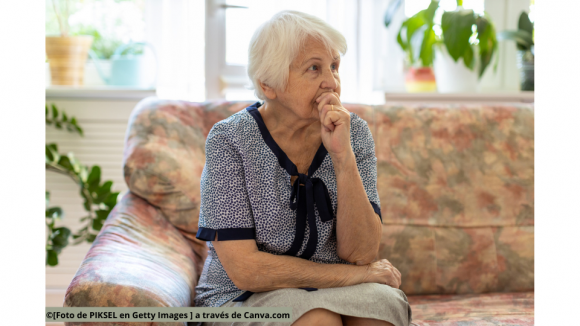 Mujer mayor sentada en el sofá de su casa.